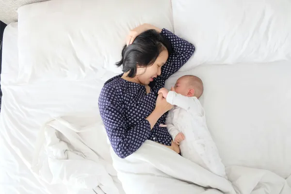 Mãe deitada na cama com o recém-nascido