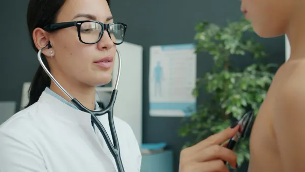 Médica de estetoscópio examina um menino no consultório
