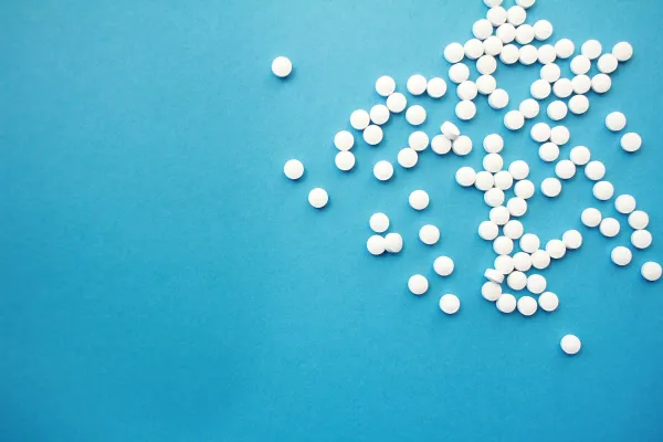 Comprimidos brancos espalhados sobre uma superfície azul