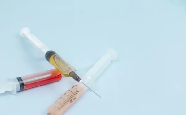 Seringas com medicamento sobre uma superfície azul clara